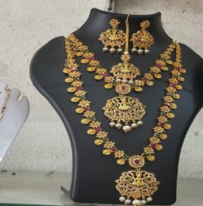 సాంప్రదాయ సోయగంతో మెరిసే టోన్ టెంపుల్ నెక్లెస్ సెట్ – దేవతా ఆకృతులతో, రూబీ-ఎమరాల్డ్ రాళ్ల అలంకరణతో, ముత్యాల తళుకులతో అద్భుతంగా రూపొందించబడిన సంప్రదాయ ఆభరణం యొక్క చిత్రం